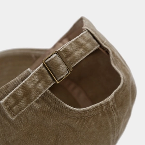 Detailed close-up of retro washed corduroy baseball cap with adjustable bronze metal buckle