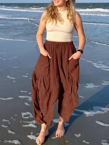 Detail of high waisted brown cotton linen wide leg pants with pockets on a beach