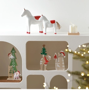 Detail of wooden Christmas ornaments featuring white dala horse and Santa with warm lighting