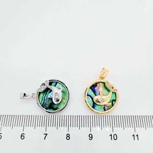 Detail view of 18K gold plated whale pendant with abalone shell and ruler for size scale