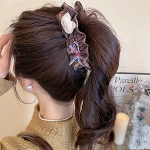 Détail d'une pince à cheveux à carreaux marron avec ours en peluche et noeud