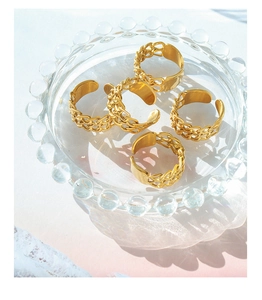 Detail view of five gold-plated chain link rings on a decorative glass tray
