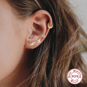 Detail of 925 sterling silver ear piercings featuring floral and butterfly diamond studs