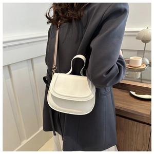 White minimalist leather saddle bag styled on model with a striped wide shoulder strap