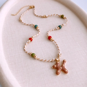 Detail of woven rope necklace featuring colorful ceramic beads and a brown puppy pendant