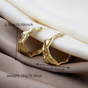 Detailed view of gold irregular metal earrings on silk with size and weight specs