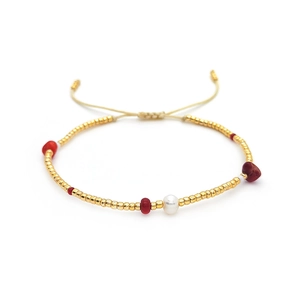 Bohemian beaded bracelet with gold beads, red stones, and freshwater pearls on white