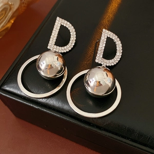 Macro detail of silver D-letter earrings with crystals and metal spheres on leather