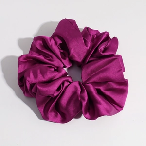 Close-up of the glossy purple satin fabric texture on a soft oversized scrunchie
