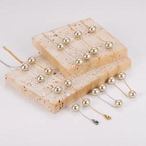 Elegant gold and silver layered pearl necklaces draped on minimalist beige stone blocks
