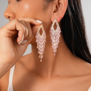 Elegant gold drop earrings with pink cubic zirconia tassels worn by a model on grey background