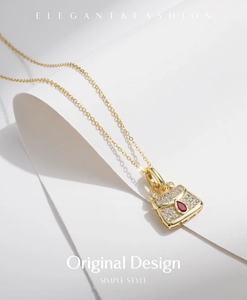 Detail of gold necklace with handbag pendant set with clear diamonds and red ruby
