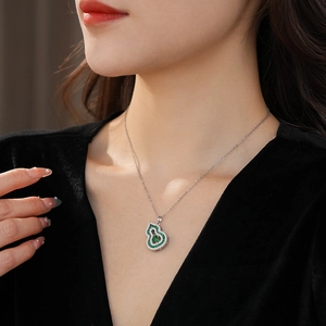 Close-up of emerald green zircon gourd pendant on a silver necklace worn by a model