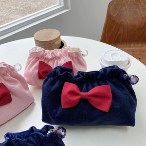 Detail of waffle fabric cosmetic bags with red bows and crystal drawstring beads
