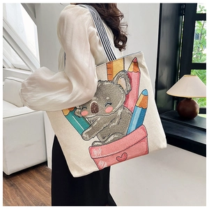 Detail of the linen tote bag featuring cartoon koala embroidery and striped shoulder strap