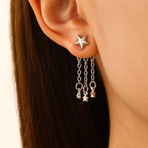 Détail de boucles d'oreilles étoile en argent avec longues chaînes à pompons