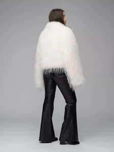 Back view of a white faux fur jacket with fluffy texture and black leather trousers