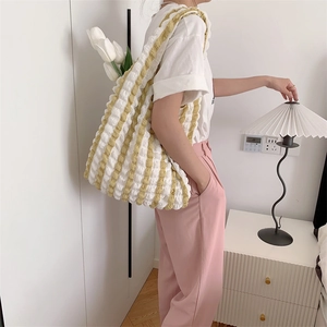 Detailed view of yellow and white striped bubble texture tote bag worn on shoulder