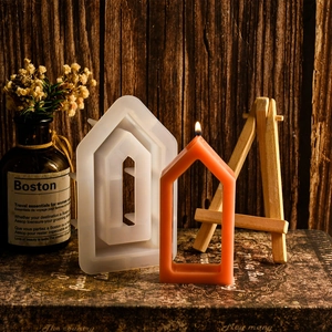 Detailed view of hollow house silicone mold and orange beeswax candle on vintage books