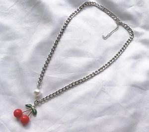 Detailed view of silver alloy necklace with red cherries and a white pearl pendant