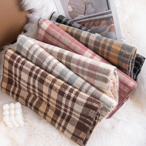 Classic British plaid wool scarves in multiple colors neatly stacked on a soft white rug