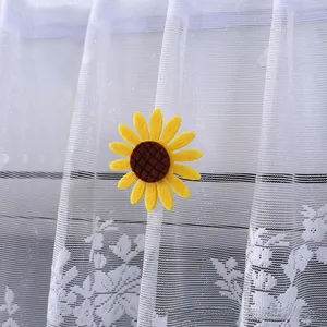 Close-up of a felt sunflower decorative accessory on a white lace curtain panel