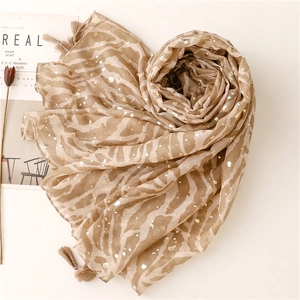Detail of light brown scarf featuring zebra patterns, gold foil accents and fringe