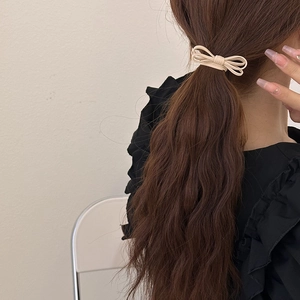 Beige bow hair tie for women styled on a ponytail with a minimalist fabric design