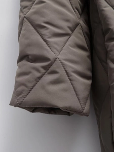 Macro detail of diamond quilted stitching and elastic cuff on brown hooded cotton coat
