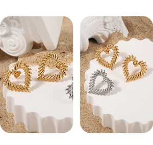 Detailed view of hollow heart stud earrings with textured gold and silver finishes