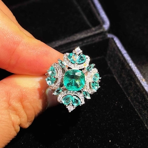 Macro view of micro-pave emerald cut green gemstone ring with sparkling diamonds