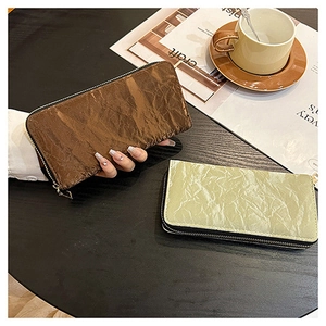 Detailed view of long zip wallets in brown and green with wrinkled texture finish