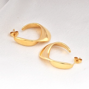 Minimalist twisted gold C-shape stud earrings on white silk background