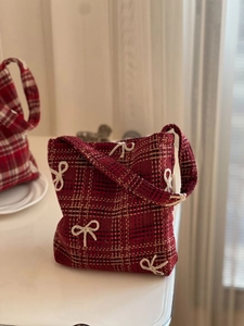 Detail of red plaid tweed handbag with white crochet bow and vintage textured fabric