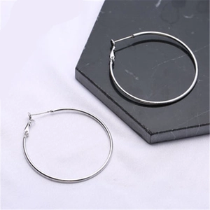 Minimalist large silver hoop earrings for women on black and white marble background