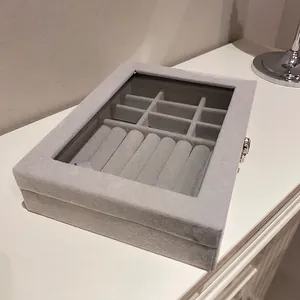 Gray velvet jewelry box with glass lid featuring 12 compartments and ring storage slots