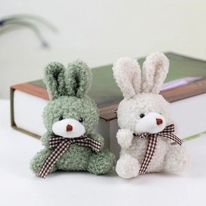 Close-up of plush rabbit charms in green and off-white with checkered bow ties