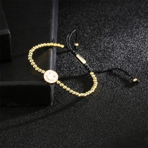 Dettaglio del bracciale regolabile a sfere dorate con ciondolo smiley in smalto bianco