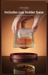 Detailed view of striped whiskey glass spinning on its round wooden coaster base