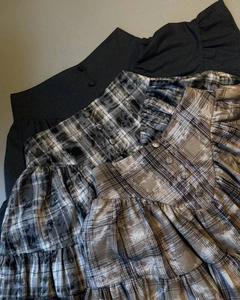 Close-up of high-waist plaid and black skirts featuring ruffled layers and button details