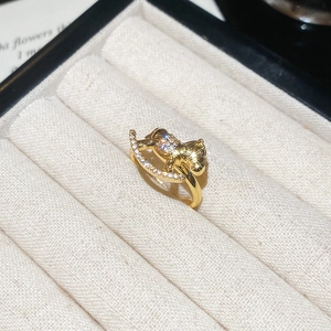 Macro shot of gold rocking horse ring featuring micro-pave cubic zirconia on a beige box