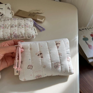 Detailed macro of a quilted cotton coin purse featuring cute animal patterns and pink zipper pull