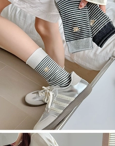 Nahaufnahme von grau-weiß gestreiften Baumwollsocken mit süßer Bärenkopf-Stickerei