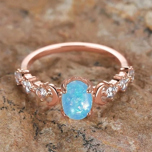 Macro detail of oval blue opal ring with rose gold moon accents and white zircons