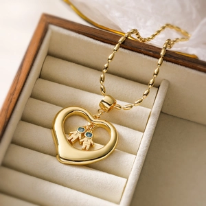 Golden heart pendant necklace with two tiny figures and blue gems in a wooden box