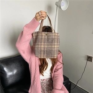 Close-up of retro plaid fabric tote bag with brown handles and central metal button detail