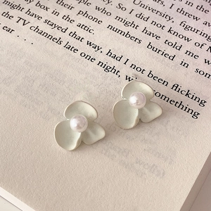 Close-up of matte white flower earrings with pearls on an open book page