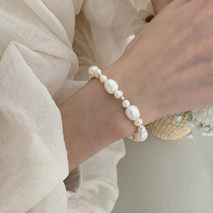 Detail of freshwater pearl bracelet with gold beads worn on a model wrist