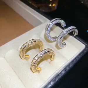Sparkling C-shaped stud earrings with pavé zircons in gold and silver finishes
