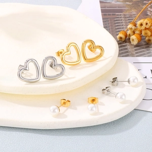 Gros plan de boucles d'oreilles cœurs ajourés et perles en finitions or et argent